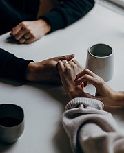 two people holding hands on a table with coffe